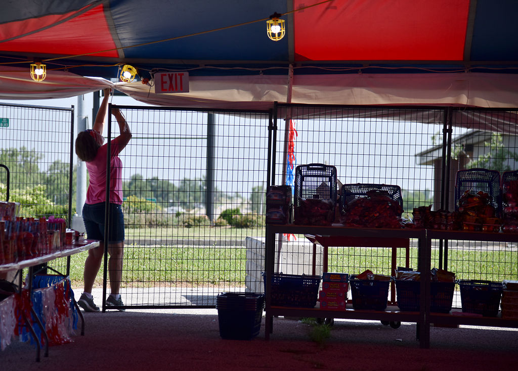 Dyann Butcher readjusts the metal door to her fireworks stand Wednesday at the Christmas in July stand